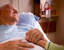 Old man lying in hospital bed holding daugher Canada’s hospital system ill-prepared for COVID-19 crisis