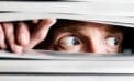 Scared man looking through slats of a blind Do you suffer from a false sense of no confidence?